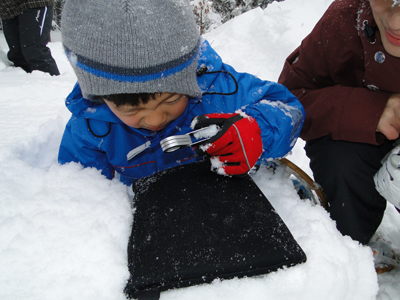 雪をルーペで観察する子ども